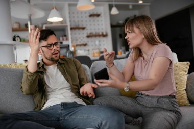 Erkek arkadaşı ve kız arkadaşı kanepede tartışıyor. Kızgın kadın erkek arkadaşına bağırıyor..