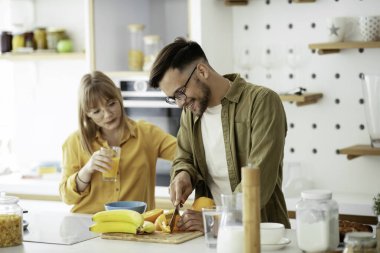 Genç çift evde kahvaltı hazırlıyor. Sevgi dolu çift mutfakta eğleniyor..