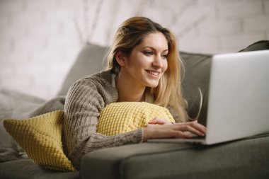 Güzel sarışın kadın dizüstü bilgisayarında film izliyor..