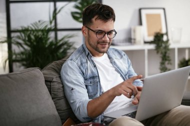 Adam evde çalışıyor, dizüstü bilgisayar kullanıyor.