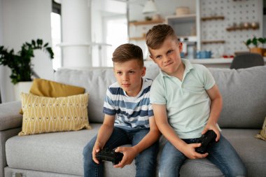 Video oyunu oynayan mutlu kardeşler. Küçük kardeşler oturma odasında video oyunu oynarken eğleniyorlar.