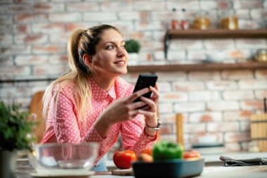 Mutfaktaki kadın. Mutfakta telefon kullanan güzel bir kadın..