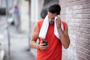 Genç sporcu dışarıda koşuyor. Açık hava eğitiminden sonra yakışıklı bir adam dinleniyor..