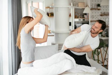 Çift evde eğleniyor, yastıklarla kavga ediyor.