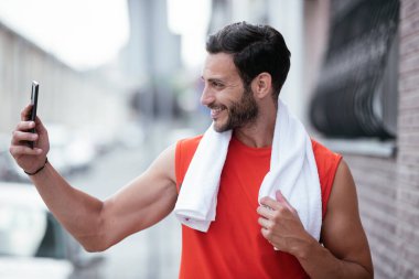 Genç sporcu dışarıda koşuyor. Açık hava eğitiminden sonra yakışıklı bir adam dinleniyor..