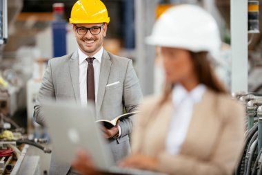 Fabrika müdürü ve mühendisi teftiş yapıyor. İş adamı ve işkadını üretim hattında.