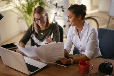 İki iş kadını ofiste iş hakkında konuşuyor.