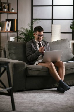 Evde pantolonsuz çalışan bir iş adamı. Genç adam video görüşmesi sırasında bilgisayarı kullanıyor..