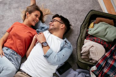 Genç çift yolculuk için hazırlanıyor, giysilerini seyahat çantasına koyuyorlar. Erkek arkadaş ve kız arkadaş geziye hazırlanıyor.
