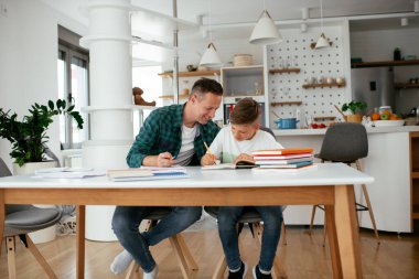 Baba, oğluna ev ödevinde yardım ediyor. Küçük çocuk evde öğreniyor..