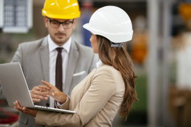 Fabrika müdürü ve mühendisi teftiş yapıyor. İş adamı ve işkadını üretim hattında.