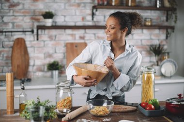 Güzel bir kadın yemek pişiriyor ve mutfakta eğleniyor. Kız mutfakta sağlıklı yemek pişiriyor..