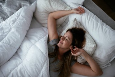 Genç ve güzel bir kadın yatakta dinleniyor. Yatakta yatan kız..