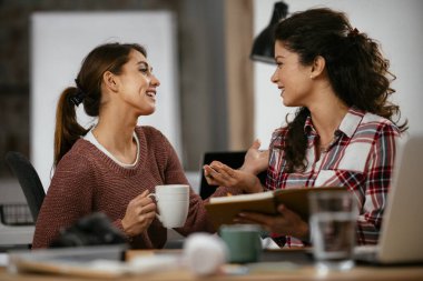 Açık uzay ofisinde konuşan ve gülen mutlu iş kadınları