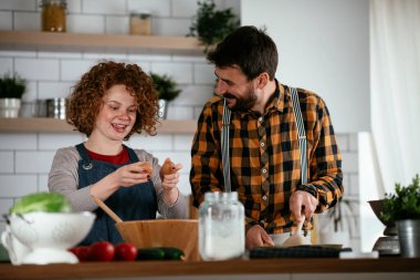 Erkek arkadaş ve kız arkadaş evde lezzetli yemekler yapıyor. Aşkın çifti mutfakta yemek pişiriyor.