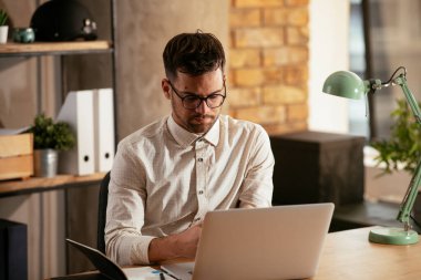 Ofiste dizüstü bilgisayarıyla çalışan bir iş adamı. Ofiste bir proje üzerinde çalışan şık bir işadamı..