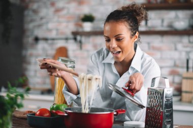 Güzel bir kadın yemek pişiriyor ve mutfakta eğleniyor. Kız mutfakta sağlıklı yemek pişiriyor..