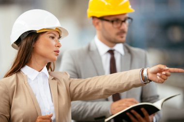 Fabrikadaki iş adamı ve iş kadını. Fabrika üretim hattında kalite kontrolde çalışan iki profesyonel insan..