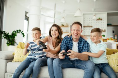 Anne ve baba evde çocuklarla video oyunu oynarken eğleniyorlar..