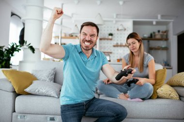 Karı koca oturma odasında joysticklerle oyun oynuyorlar. Sevgili çift evde video oyunu oynuyor..