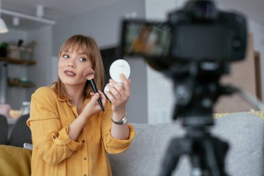 Kadın video kaydedicisi, kanalı için makyaj dersi kaydediyor. Sosyal medyada paylaşmak için makyaj dersi alan genç ve güzel bir kadın..