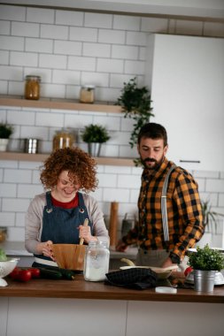 Erkek arkadaş ve kız arkadaş evde lezzetli yemekler yapıyor. Aşkın çifti mutfakta yemek pişiriyor.