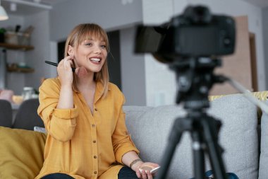 Kadın video kaydedicisi, kanalı için makyaj dersi kaydediyor. Sosyal medyada paylaşmak için makyaj dersi alan genç ve güzel bir kadın..
