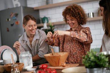 Kadın arkadaşlar mutfakta eğleniyor. Kardeşler birlikte yemek pişirir..