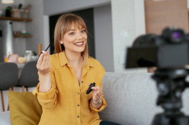 Kadın video kaydedicisi, kanalı için makyaj dersi kaydediyor. Sosyal medyada paylaşmak için makyaj dersi alan genç ve güzel bir kadın..