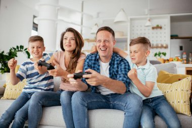 Anne ve baba evde çocuklarla video oyunu oynarken eğleniyorlar..