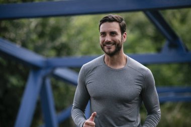 Genç adam şehirde koşuyor. Dışarıda antrenman yapan mutlu bir sporcu.