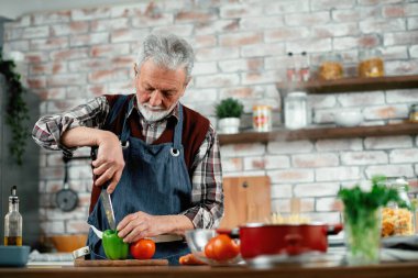 Yaşlı adam yemek yapıyor. Mutfakta kıdemli adam var..