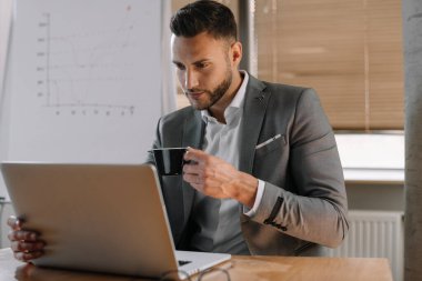 Genç iş adamı ofiste dizüstü bilgisayarla çalışıyor. Ofis masasında oturan iş adamı dizüstü bilgisayarla çalışıyor..