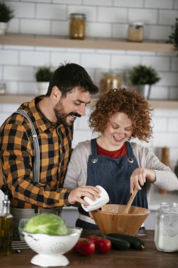 Erkek arkadaş ve kız arkadaş evde lezzetli yemekler yapıyor. Aşkın çifti mutfakta yemek pişiriyor.