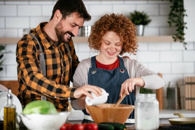 Erkek arkadaş ve kız arkadaş evde lezzetli yemekler yapıyor. Aşkın çifti mutfakta yemek pişiriyor.