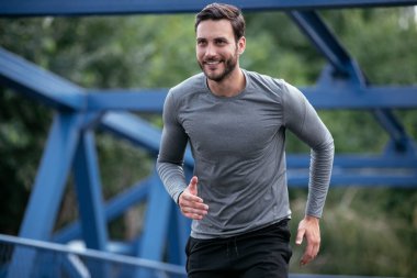 Genç adam şehirde koşuyor. Dışarıda antrenman yapan mutlu bir sporcu.