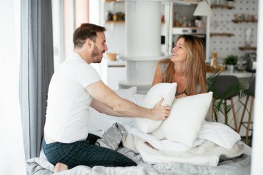 Çift evde eğleniyor, yastıklarla kavga ediyor.