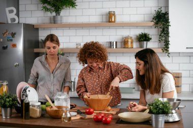 Kadın arkadaşlar mutfakta eğleniyor. Kardeşler birlikte yemek pişirir..