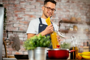 Mutfakta makarna hazırlayan yakışıklı adam. Lezzetli yemek pişiren adam..