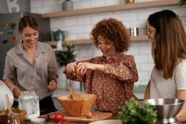 Kadın arkadaşlar mutfakta eğleniyor. Kardeşler birlikte yemek pişirir..