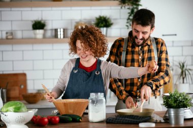 Erkek arkadaş ve kız arkadaş evde lezzetli yemekler yapıyor. Aşkın çifti mutfakta yemek pişiriyor.