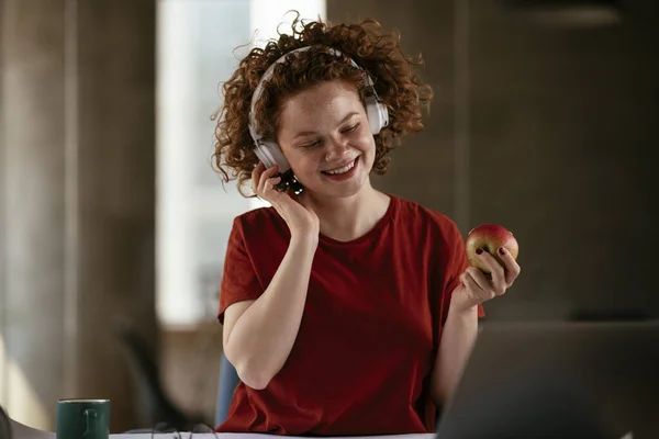 Gadis Cantik Memakai Headphone Dan Makan Apel Tempat Kerjanya — Stok Foto
