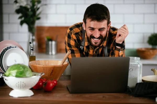 Portrait of handsome man in kitchen. Young man cooking while having video call.