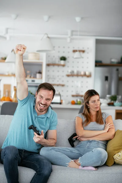 Karı koca oturma odasında joysticklerle oyun oynuyorlar. Sevgili çift evde video oyunu oynuyor..
