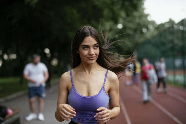 漂亮的女子在跑道上训练 穿着蓝色运动服的年轻女子 — 图库照片
