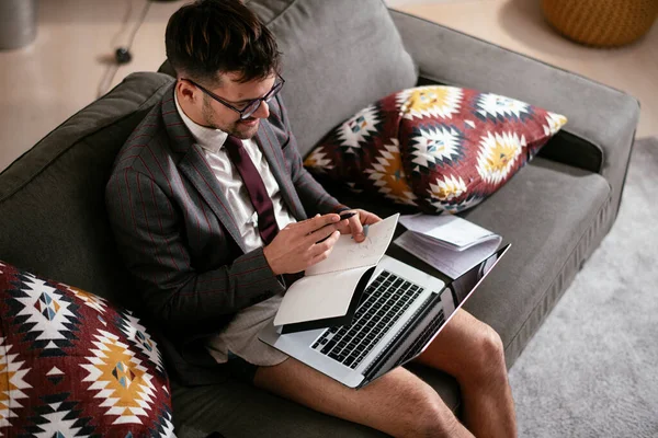 Evde pantolonsuz çalışan bir iş adamı. Genç adam video görüşmesi sırasında bilgisayarı kullanıyor..