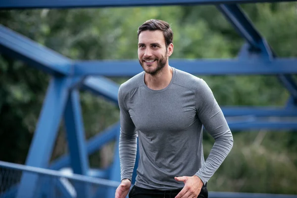 Young man jogging in the city. Happy athlete training outdoors