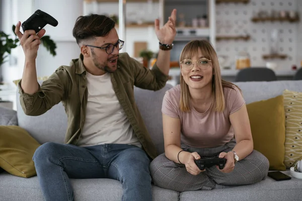 Beautiful young couple playing video games at home.