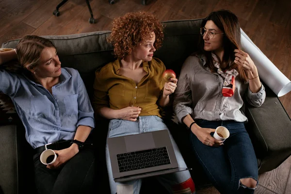 Happy businesswomen talking and laughing in office. Beautiful women on coffee break.