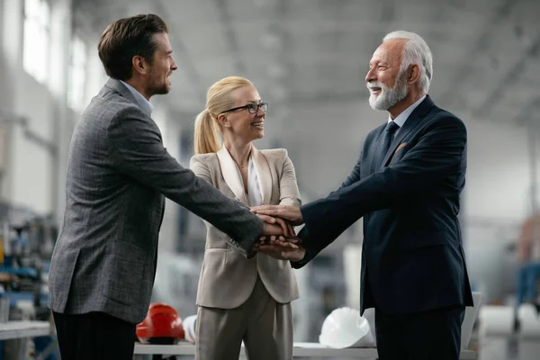 Başarılı bir takım. İş adamları ellerini fabrikada birleştiriyor.